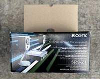 Photo showing the Sony SRS-Z1 speaker system box with graphical representation of speakers and amplifier unit, emphasizing its compact design and features.