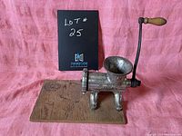 Side view of antique Keystone meat grinder mounted on plywood base with crank handle visible.