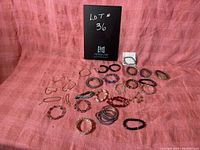 Overall view of 27 assorted vintage costume jewelry bracelets laid on pink cloth background.