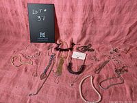 Full view of all necklaces in the lot laid out on a pink cloth background with lot sign