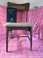 Front view of the teak dining chair with cane inset at the backrest and upholstered seat.