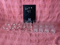 Front view of the full lot showing six small wine glasses and six highball glasses all clear glass with the lot number in the background.