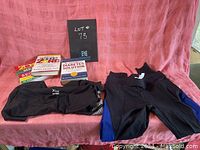 Two pairs of black workout leggings laid out with three diet and health books on a pink fabric background.
