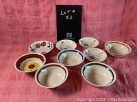 Photo showing nine mid century modern ceramic cereal bowls with varied floral and geometric painted designs on a pink background.