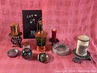 Full view of the lot showing the copper and green glass lantern, various candle holders including red pillar candle on black stand, gold candle on gold holder, marble candle holder with candle, stained glass decorative globe, small silver dish, candle with graphics on wooden stand, and a small round container with lid.