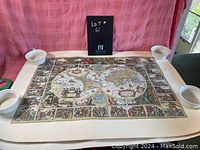 Full view of the unframed vintage old world map poster with Latin text laid flat and held in place by round white weights at the corners.