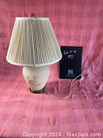 Full view of the vintage table lamp showing pleated lampshade, ceramic body with floral pattern, and brass-colored base.