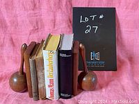 Photo of seven vintage books in German with maraca-shaped wooden bookends on pink background.
