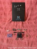 Collection of vintage brooches, earrings, and bracelet displayed on pink fabric with the seller's lot number card