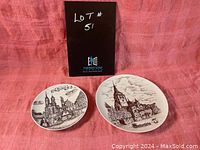 Two round vintage Porzella porcelain plates with black and white illustrations displayed side by side on a pink fabric background. An informational black placard marked Lot #51 is behind them.