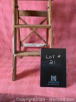 Front view of vintage wooden step ladder against pink backdrop with lot number card