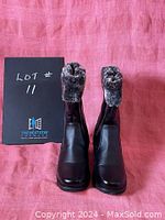 Front view of the pair of black women's boots showing the faux fur lining at the top and smooth exterior finish.