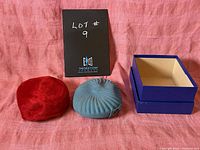 Two hats side by side: red cozy hat and blue beret with box and lot marker