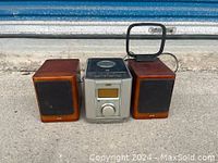 Front view of JVC stereo main unit flanked by two wooden JVC speakers, placed on floor.