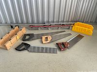 Overall view of the lot showing various hand tools including handsaws, miter boxes, level, and squares on a table.
