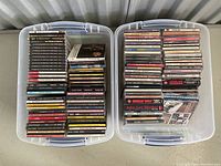 Two clear plastic totes filled with vertically stacked jewel case CDs