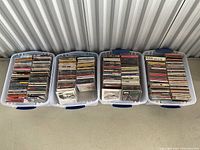 Four side-by-side plastic storage bins loaded with CDs