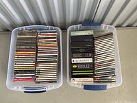 Two plastic bins filled with approximately 90 classical music CDs in jewel cases and box sets arranged vertically, showing varied titles, brands, and composers.