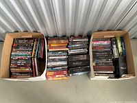 Three boxes with assorted DVD cases, a mix of single movies and TV series box sets, showing titles like Deadwood, Spider-Man, and Memento.