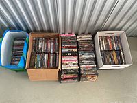 Overview of four containers filled with assorted DVDs stacked vertically and horizontally to display titles.