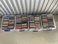 Four clear plastic storage tubs filled with stacked CD jewel cases.