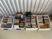 Four containers—two plastic tubs and two cardboard boxes—filled with CDs