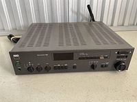 Front left angle view showing power button, multiple control knobs and switches, headphone jack, and ventilation slots on top.