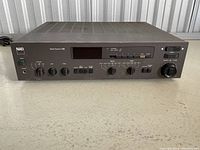 Front angled view of NAD 7155 stereo receiver showing power button, headphone jack, bass and treble knobs, input buttons, and tuning dial.