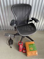 Overall view showing black mesh office chair, red Brady label maker, label cartridge and pack of bubble mailers