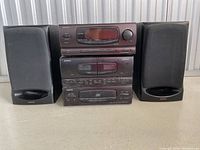 Front view of Onkyo stereo system components stacked with two speakers placed on each side on a flat surface.