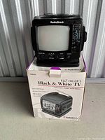 Photo of RadioShack black and white TV placed on top of its original box showing the front and screen of the 5 inch CRT.