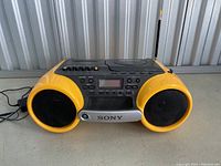 Front view showing yellow and black Sony ESP Sports portable stereo with dual speakers and antenna extended, placed on table.