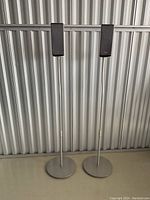 Two tall black Sony speakers mounted on silver metal stands with circular bases.