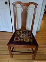 Front view showing the wooden chair with floral upholstered seat and backrest design.