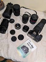 Wide view of camera body, manual, four lenses, two teleconverters, cases and straps laid out