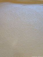 Close-up of the cream chenille bedspread texture and circular medallion pattern.