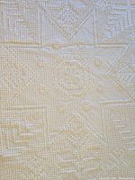 Close-up of the star medallion pattern with textured woven detailing in cream color fabric.