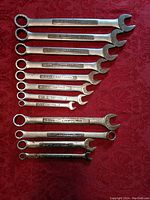 Full set of 12 Craftsman combination wrenches laid out on red fabric, showing open and box ends and etched size and brand information.