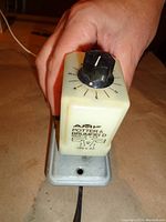 Photo showing top of Potter & Brumfield time delay relay with rotary dial and base, held in hand for scale.