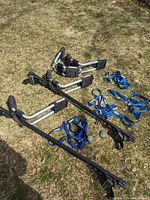 Thule roof rack crossbars with kayak cradles and tie-down straps laid on grass showing the full set and components.