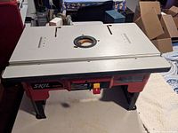 Front-top view of Skil router table with grey top and circular center hole for router bit, no fence attached.