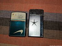 Photo of two vintage butane lighters on fabric background, showing front sides with designs.
