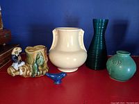Full lot showing five vintage items: ceramic planter figurine, blue ceramic bird, cream ceramic vase, teal ribbed glass vase, small green ceramic vase.
