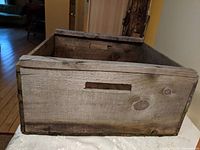 Top-front angle view of a large wooden crate showing one built-in cut-out handle and rustic wood texture.