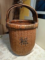 Front view showing the full wicker basket with wooden handles and visible Chinese character decoration woven into the body.