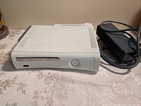 White Xbox 360 console with power supply unit and Intercooler cooling accessory visible on table.