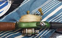 Close-up of green WondeReel casting reel attached to fishing pole with cork handle grip and wrapped white fishing line.