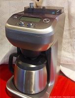 Front side view of Breville Grind Control coffee maker, showing stainless steel thermal carafe and main unit with control knobs.