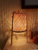 Photo of lamp lit showing warm light pattern and woven bamboo shade.