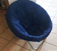 Full view of the chair set on tile floor showing circular padded royal blue seat and metal tubular frame.